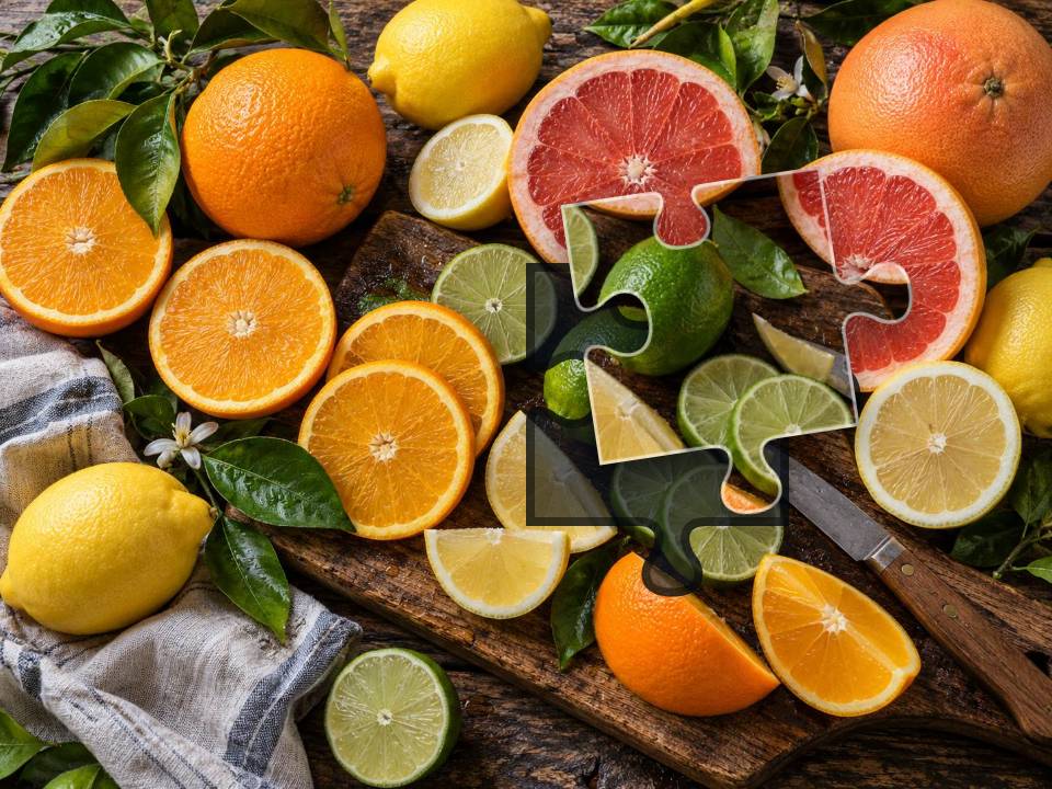 Sliced oranges, lemons, limes and pink grapefruit with green leaves on a dark wooden board.