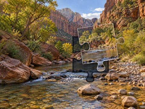 Clear shallow creek winding through red sandstone, pale pebbles, sagebrush and cottonwood trees.